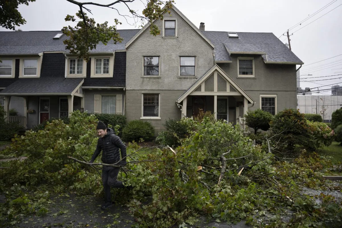A man clears limbs and debris from his street as post tropical storm Fiona causes widespread damage in Halifax on Sept. 24, 2022. (The Canadian Press/Darren Calabrese)