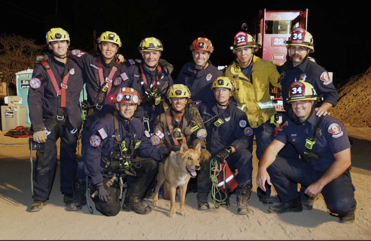 Firefighters pose with a Cesar a blind dog that was rescued from a hold in Pasadena, Calif., on Sept. 20, 2022. (Pasadena Fire Department via AP)