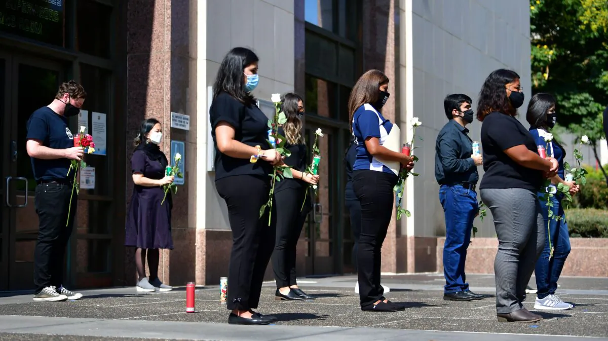 People hold roses while attending a memorial honoring residents of Los Angeles who lost their lives to coronavirus in Los Angeles on Aug. 31, 2020. (Frederic J. Brown/AFP via Getty Images)