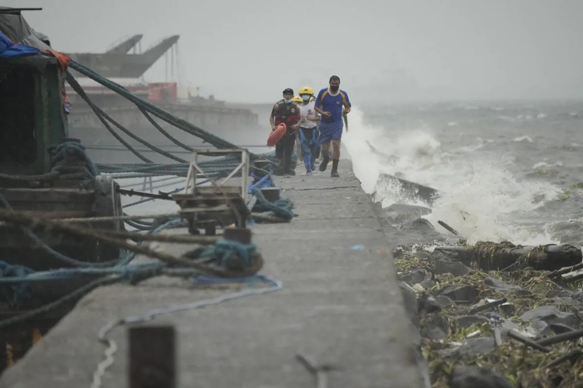 Rescuers run as they check residents living at the seaside slum district of Tondo while Typhoon Noru approaches Manila, Philippines, on Sept. 25, 2022. (Aaron Favila/AP Photo)