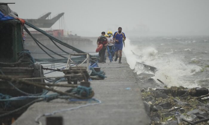 2022 年 9 月 25 日，当台风诺鲁接近菲律宾马尼拉时，救援人员在检查居住在通多海滨贫民区的居民时奔跑。（Aaron Favila/AP Photo）