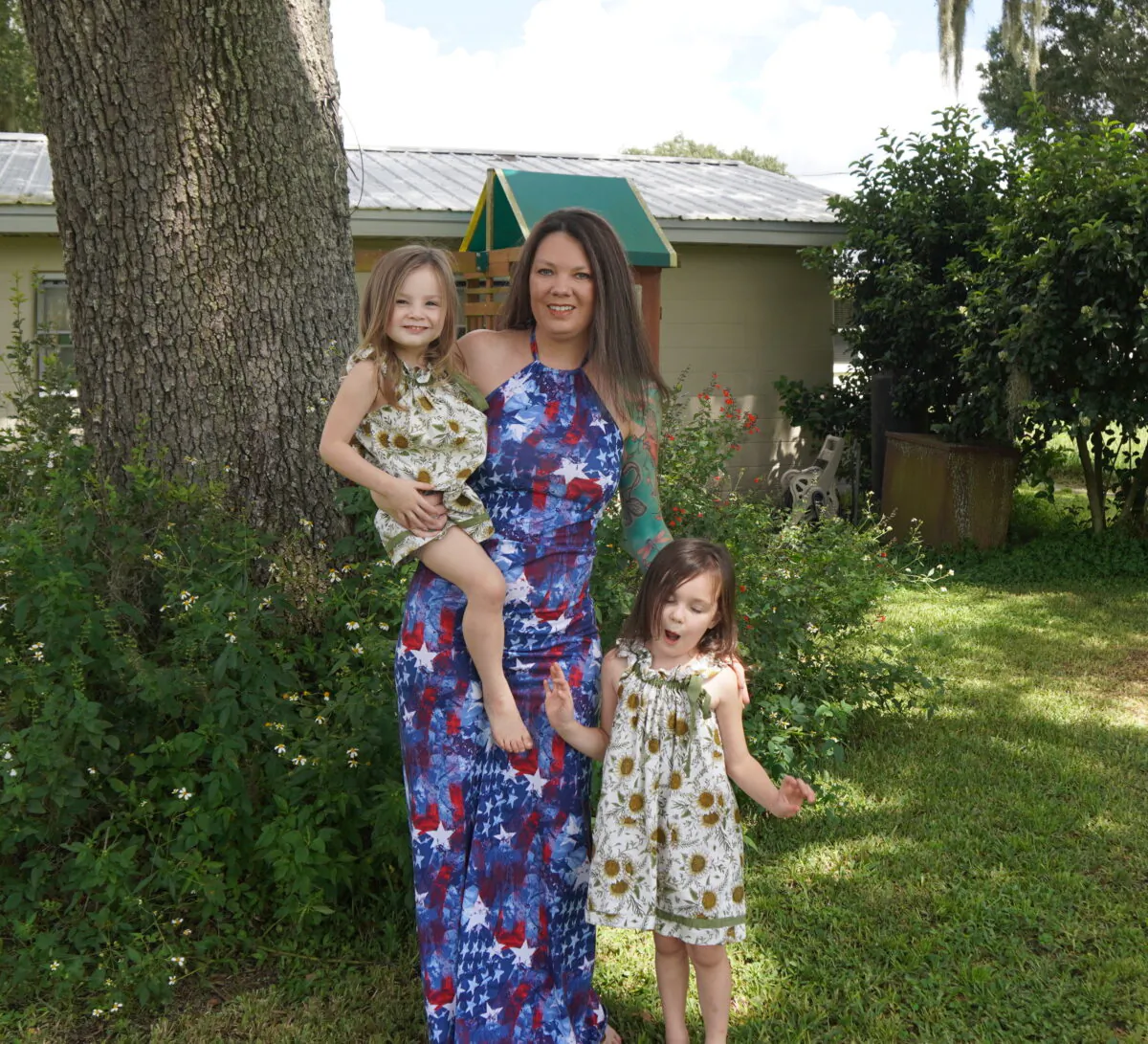 Nikki Jones holds her 3-year-old daughter Raven with her 5-year-old daughter Harley standing in front of a memory garden of wildflowers they planted in memory of husband and father Shane Jones. Sept. 20, 2022 (Jann Falkenstern/The Epoch Times)