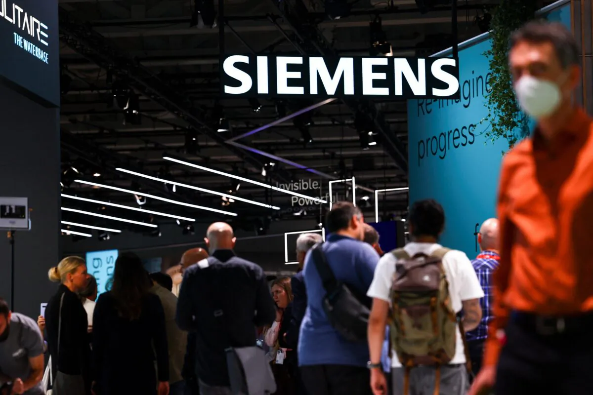 Visitors walk under a Siemens sign at the international consumer technology fair IFA in Berlin on Sept. 2, 2022. (Lisi Niesner/Reuters)