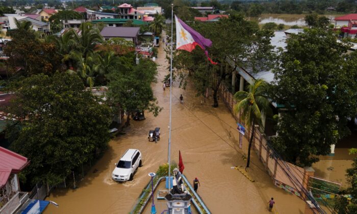 2022 年 9 月 26 日，菲律宾布拉干省圣米格尔镇的居民从台风诺鲁经过一条被洪水淹没的道路。（Aaron Favila/美联社照片）