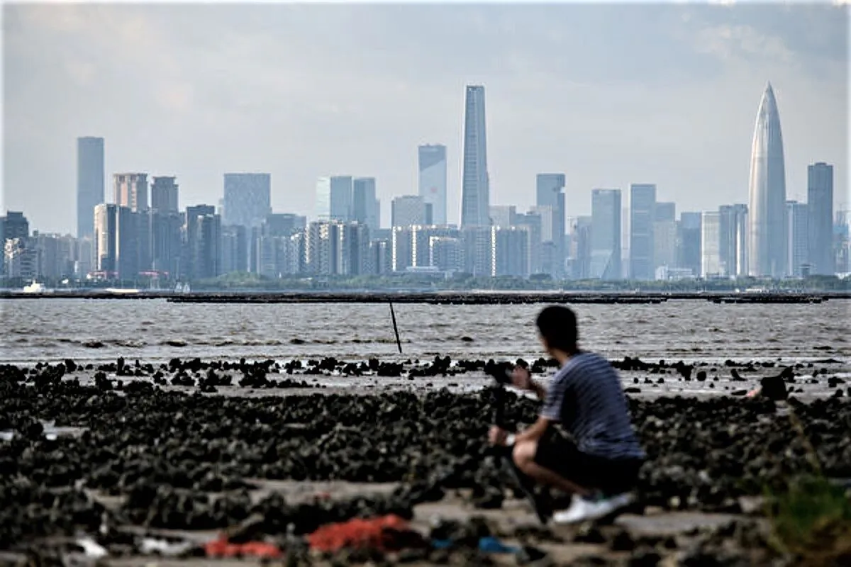 A man in Hong Kong sets up his camera as he looks across Deep Bay toward the Shenzhen skyline on Sept. 12, 2018. (Anthony Wallace/AFP via Getty Images)
