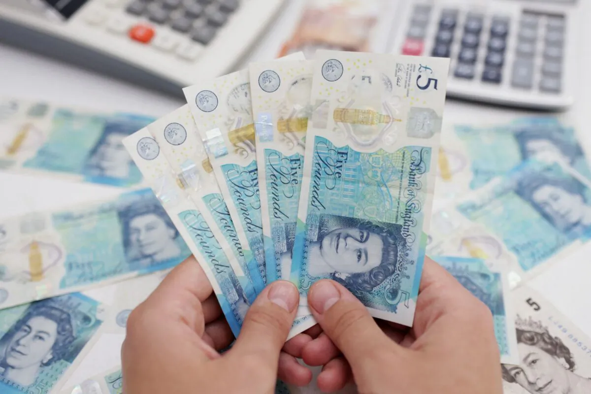 A woman holds British pound banknotes in this illustration taken on May 30, 2022. (Dado Ruvic/Reuters)