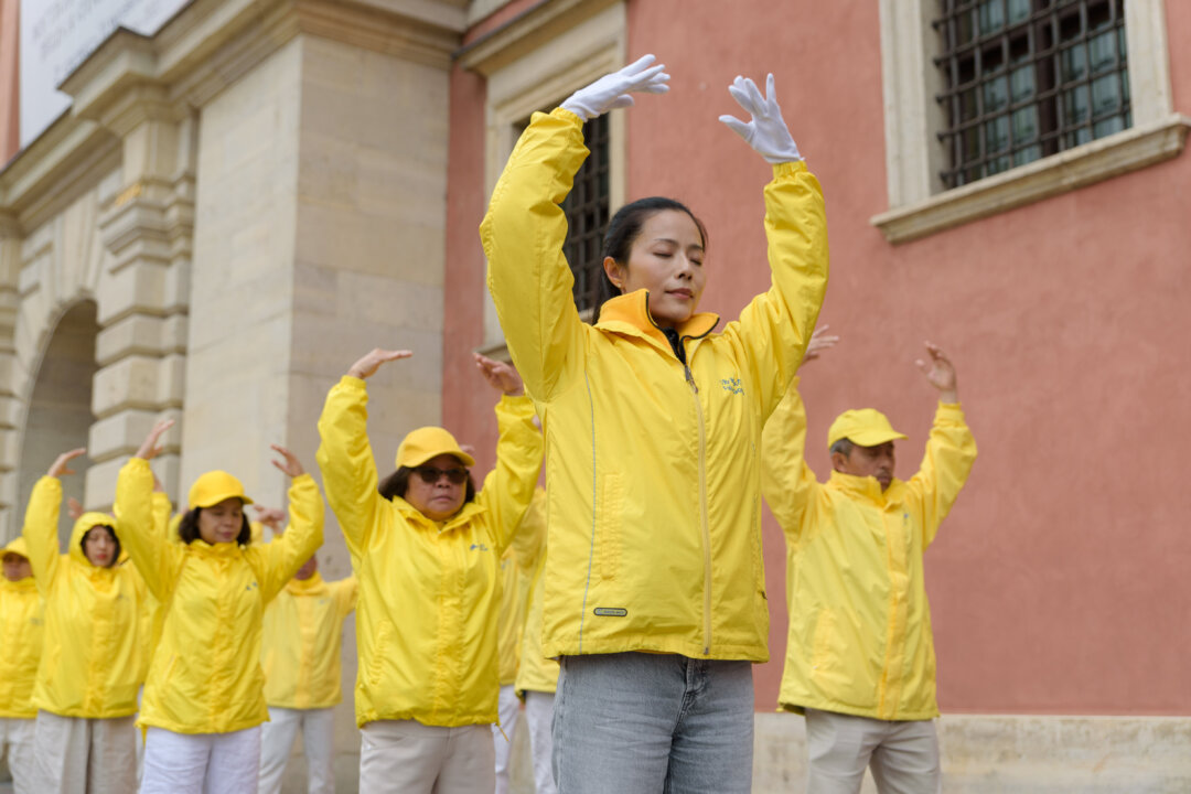 Falun Dafa practitioners meditate after a march through the center of Warsaw, Poland, on Sept. 9, 2022. (Mihut Savu/The Epoch Times)