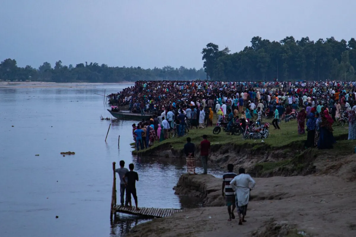 People gather along the banks of the Karatoya river after a boat capsized near the town of Boda in Bangladesh, on Sept. 25, 2022. (Firoz Al Sabah/AFP via Getty Images)