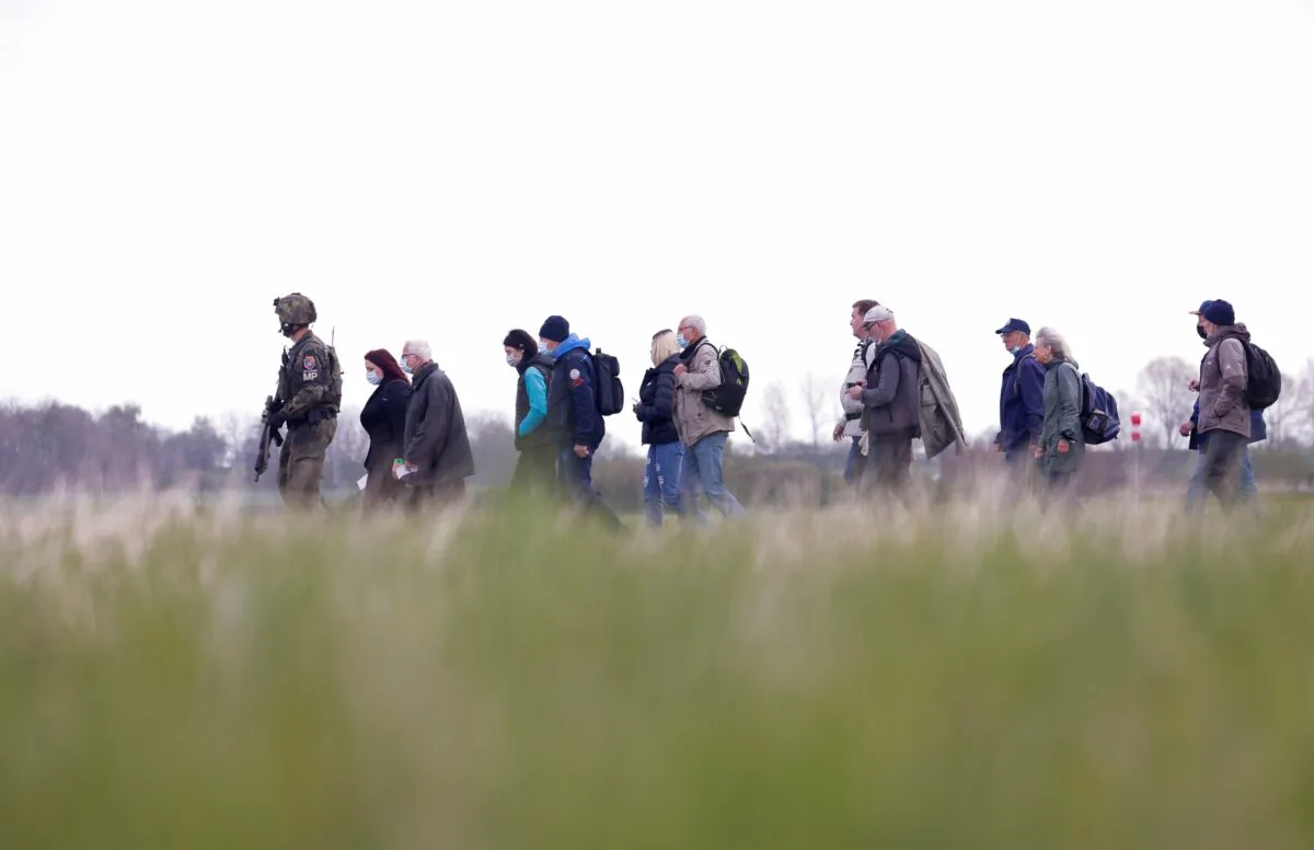 A soldier leads people during the "Schneller Adler" or "Fast Eagle" exercise of evacuation of refugees at an airport in Barth, North Germany, on May 5, 2022. (Michele Tantussi/Reuters)