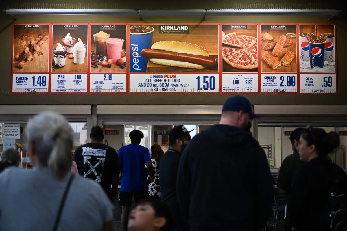 Customers wait in line to order below signage for the Costco Kirkland Signature $1.50 hot dog and soda combo, which has maintained the same price since 1985 despite consumer price increases and inflation, at the food court outside a Costco Wholesale Corp. store in Hawthorne, California, on June 14, 2022. (Patrick T. Fallon/AFP via Getty Images)