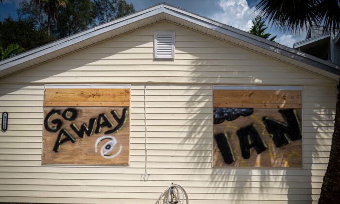 2022 年 9 月 26 日，在伊恩飓风抵达佛罗里达州坦帕市以西 25 英里的印度海岸之前，人们可以看到一栋在木板上画着“离开伊恩”的房子。（Ricardo Arduengo/AFP via Getty图片）