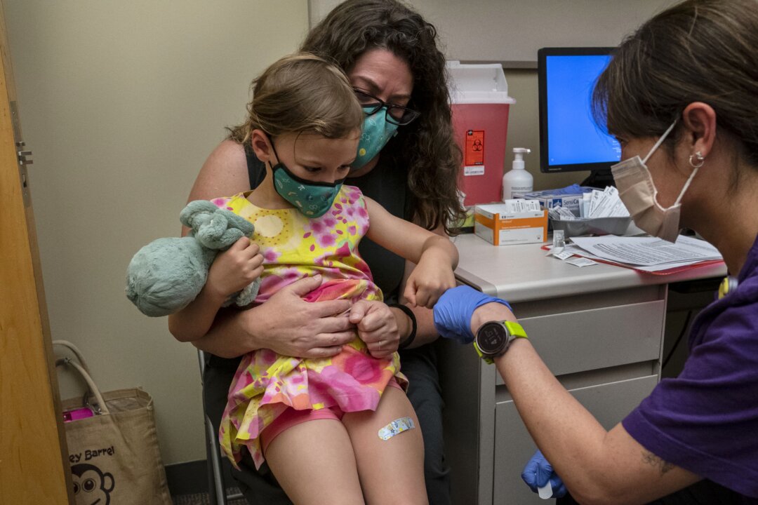 Nora Burlingame, 3, sits on the lap of her mother, Dina Burlingame, and gets a fist bump from nurse Luann Majeed after receiving her first dose of the Pfizer COVID-19 vaccination at UW Medical Center-Roosevelt in Seattle, Wash., on June 21, 2022. (David Ryder/Getty Images)