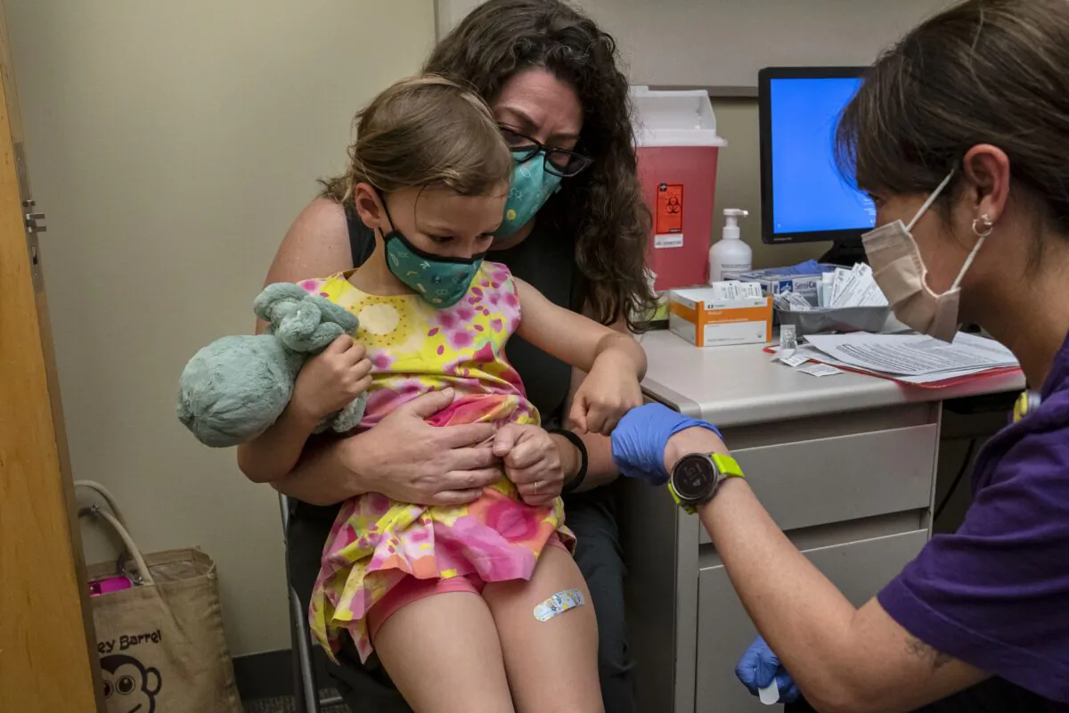 Nora Burlingame, 3, sits on the lap of her mother, Dina Burlingame, and gets a fist bump from nurse Luann Majeed after receiving her first dose of the Pfizer COVID-19 vaccination at UW Medical Center-Roosevelt in Seattle, Wash., on June 21, 2022. (David Ryder/Getty Images)