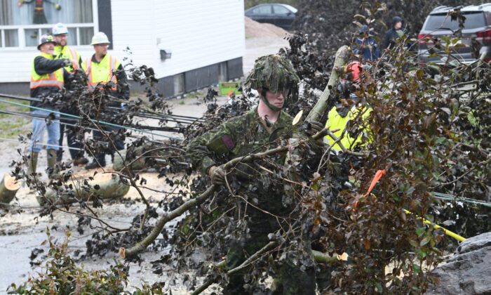Cpl. Owen Donovan of the Cape Breton Highlanders removes brush under the direction of Nova Scotia Power officials along Steeles Hill Road in Glace Bay, N.S., Sept. 26, 2022.(The Canadian Press/Vaughan Merchant)