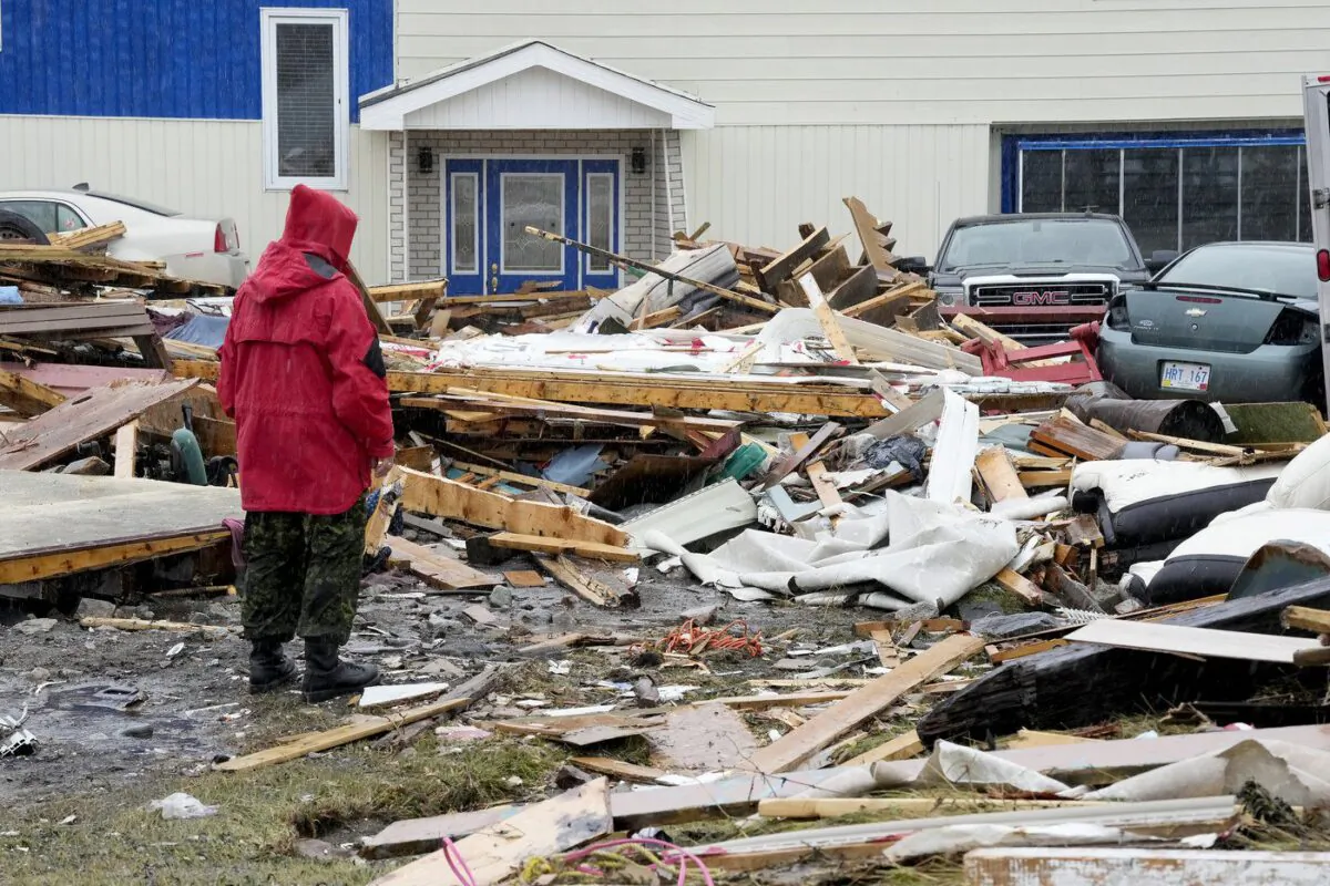 A Canadian Forces Ranger examines damage to a home in Port aux Basques, N.L., Monday, Sept. 26, 2022. (The Canadian Press/Frank Gunn)