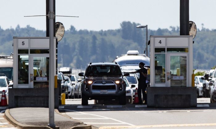 A Canada Border Services Agency officer hands documents back to a motorist entering Canada at the Douglas-Peace Arch border crossing, in Surrey, B.C., on Aug. 9, 2021. (The Canadian Press/Darryl Dyck)