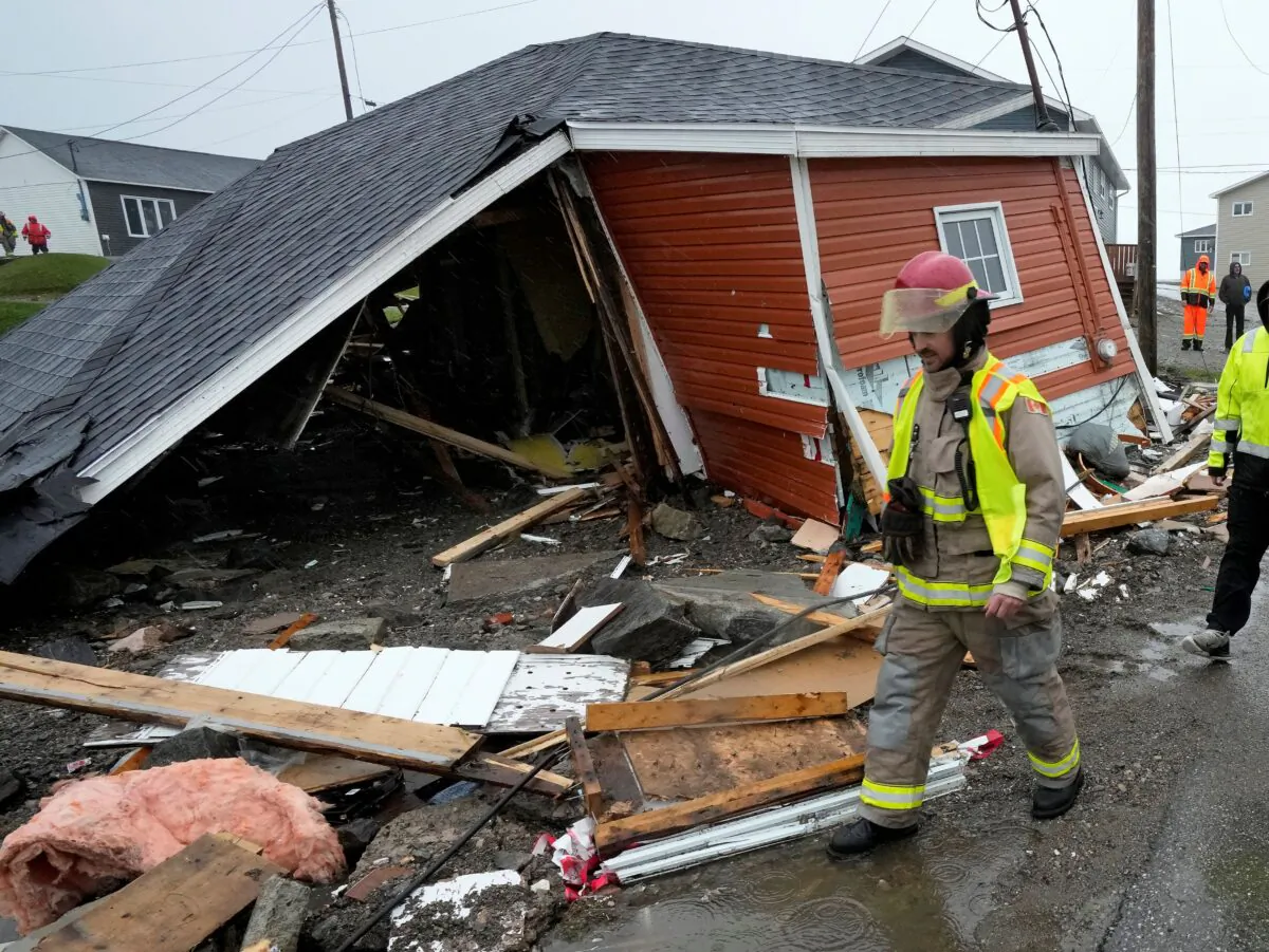 A firefighter examines damage to a home in Port aux Basques, N.L., on Sept. 26, 2022. (The Canadian Press/Frank Gunn)