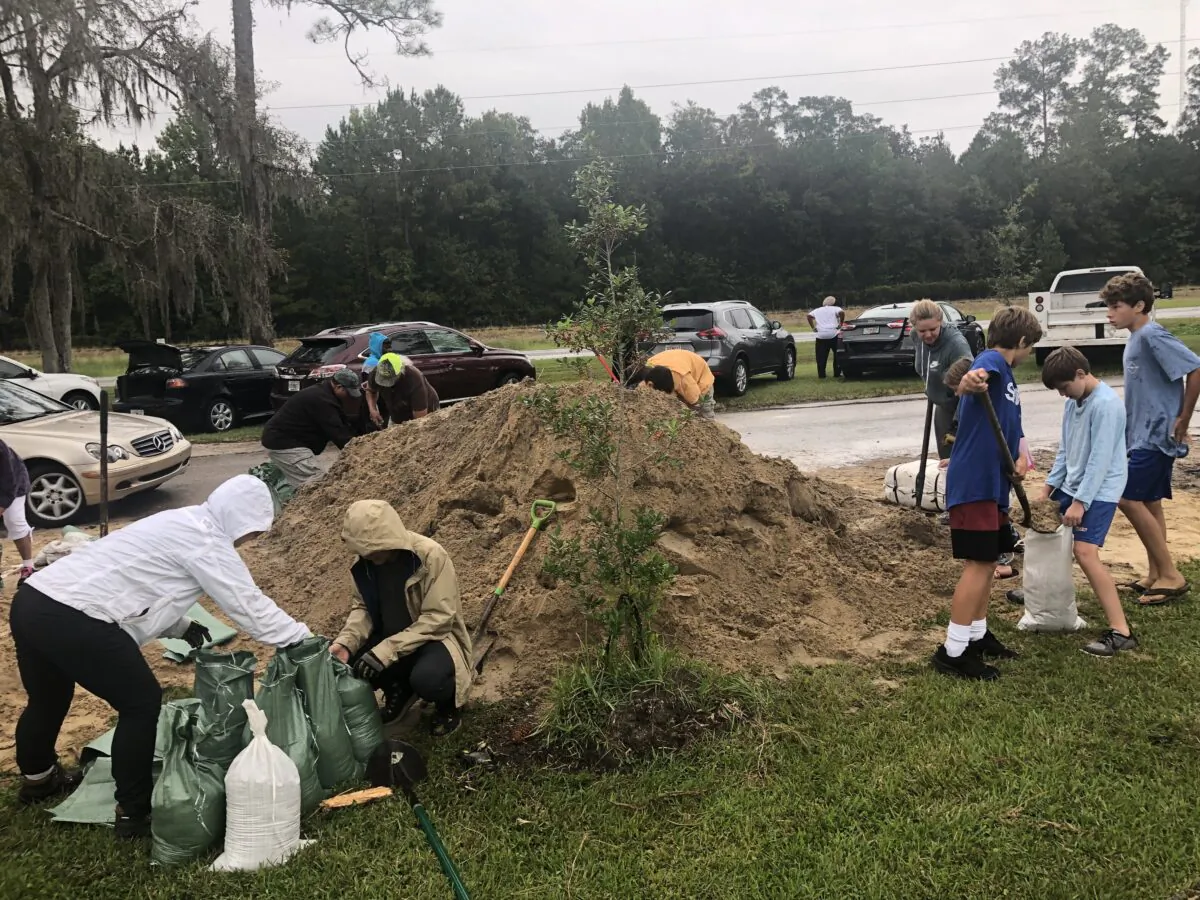 As the first rain from Hurricane Ian begins to fall in North Central Florida on Sept. 28, Alachua County residents fill sandbags at do-it-yourself stations using shovels brought from home. (Nanette Holt/The Epoch Times)
