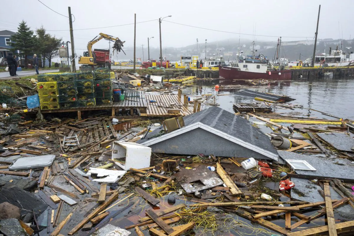 Heavy machinery clears up washed-up buildings and rubble in the harbour in Burnt Island, Newfoundland and Labrador on Sept. 27, 2022. (The Canadian Press/Frank Gunn)
