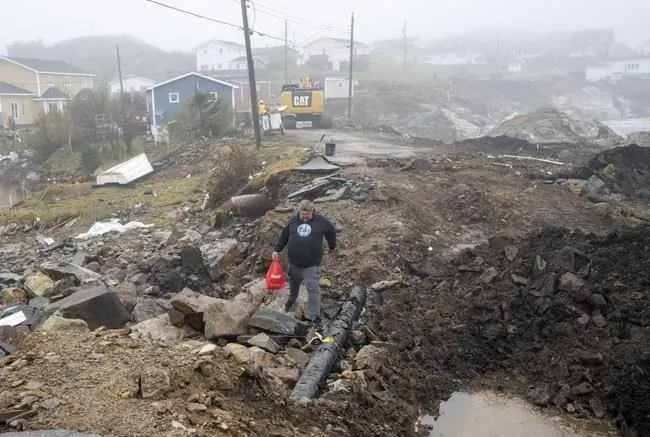 Lindsey Fudge carries groceries through the devastation left by hurricane Fiona in Burnt Island, Newfoundland on Sept. 28, 2022. (The Canadian Press/Frank Gunn)