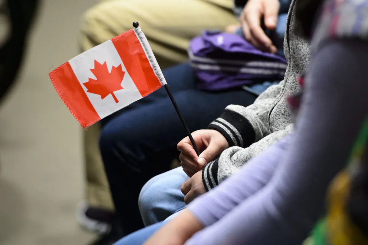 A young new Canadian holds a flag as she takes part in a citizenship ceremony on Parliament Hill in Ottawa on April 17, 2019. (The Canadian Press/Sean Kilpatrick)
