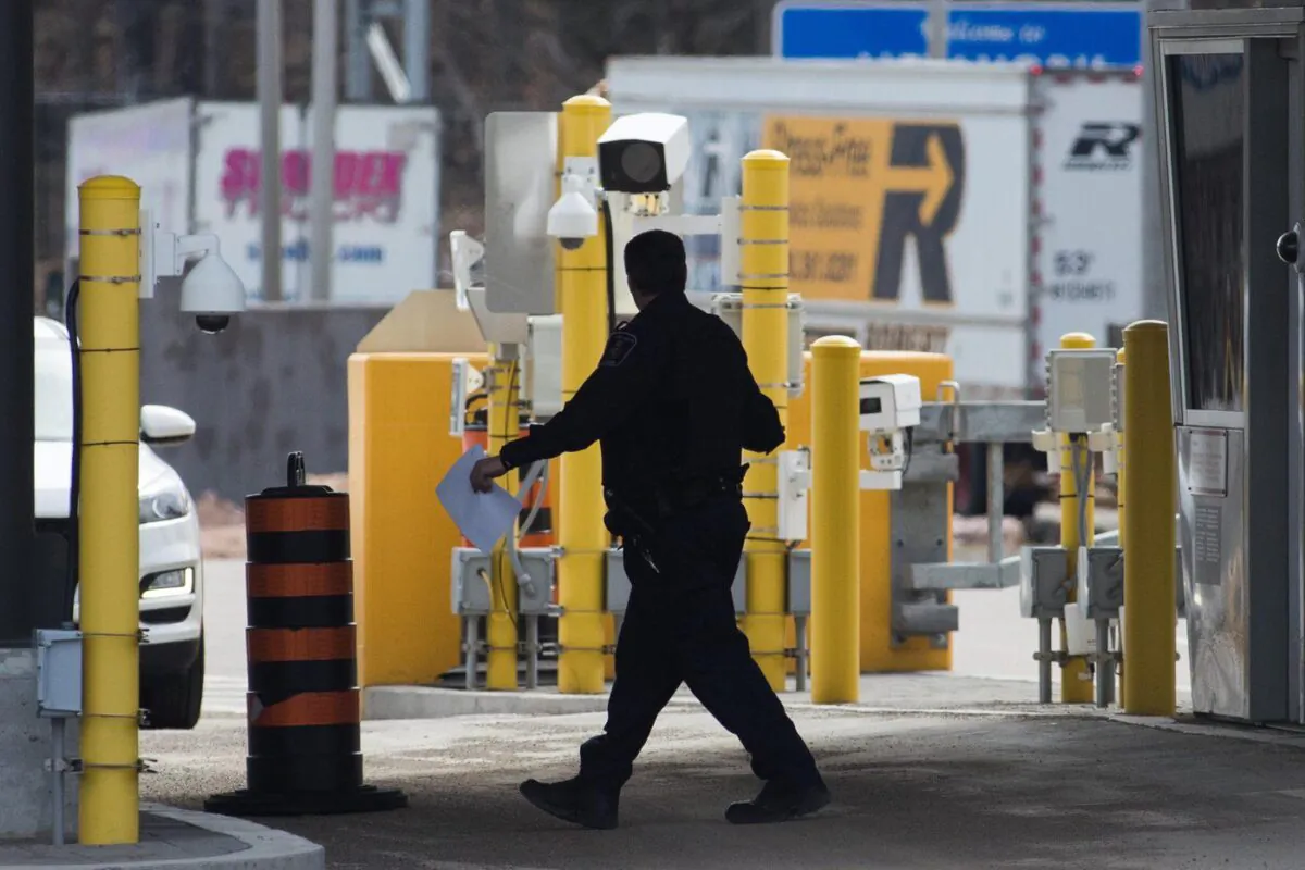 A border officer walks past security cameras at the Thousand Islands border, near Gananqoue, Ont., Mar. 16, 2020. (The Canadian Press/Lars Hagberg)