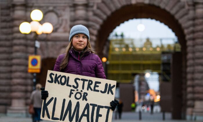 2021 年 11 月 19 日，瑞典气候活动家 Greta Thunberg 在斯德哥尔摩的瑞典议会 (Riksdagen) 前抗议时，她举着“为气候而罢工”的标语摆姿势拍照。（Jonathan Nackstrand/AFP via Getty Images）