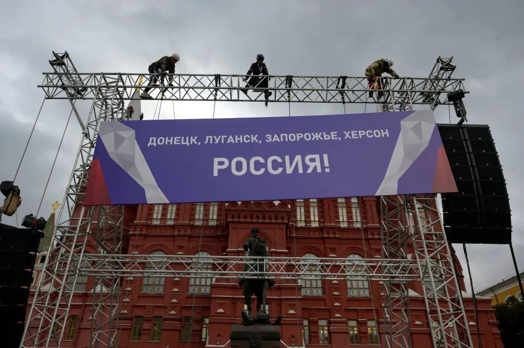 Workers fix a banner reading "Donetsk, Lugansk, Zaporizhzhia, Kherson—Russia!" on top of a construction installed in front of the State Historical Museum outside Red Square in central Moscow on Sept. 29, 2022. (Natalia Kolesnikova/AFP via Getty Images)