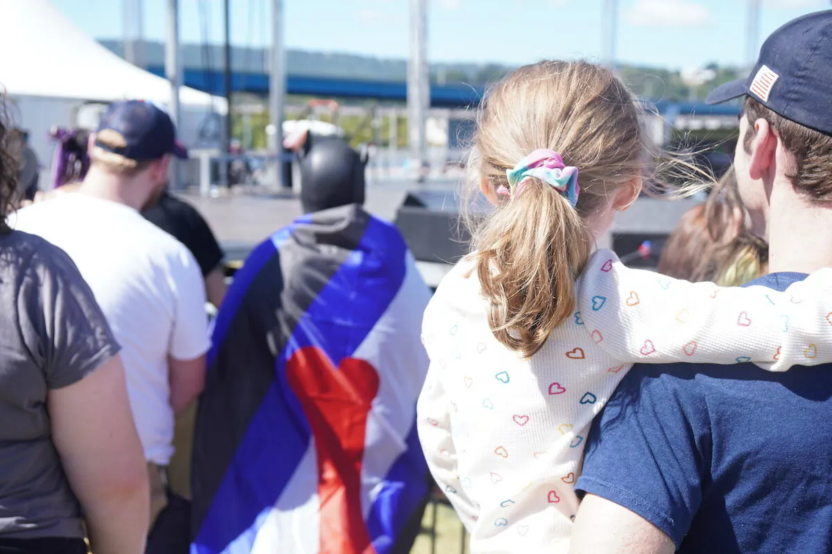 A little girl watches a man wearing a dog mask and flag that indicates he likes to pretend to be a dog at the Chattanooga Pride parade in Chattanooga, Tenn. on Oct. 2, 2022. (Jackson Elliott/The Epoch Times)