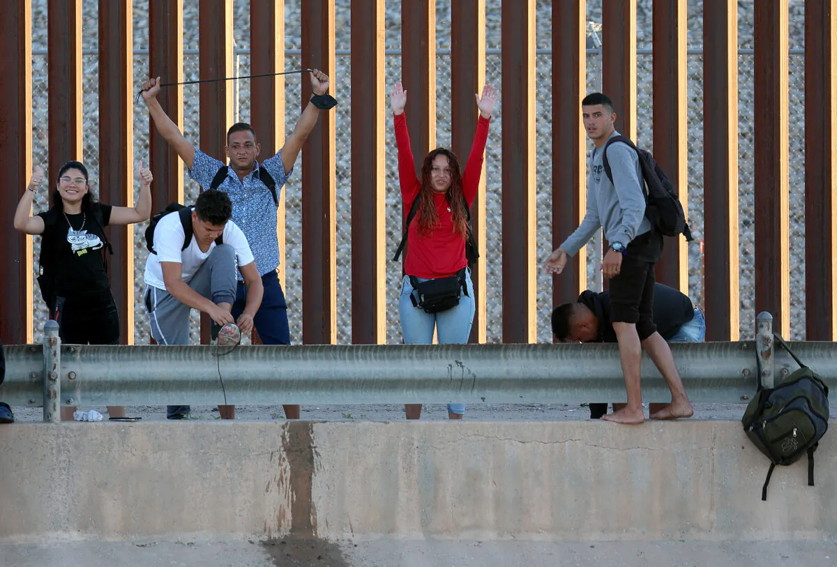 Venezuelan migrants gesture as they reach the U.S. border fence to turn themselves in to the U.S. Border Patrol after crossing the Rio Grande from Mexico in El Paso, Texas on Sept. 22, 2022. (Joe Raedle/Getty Images)