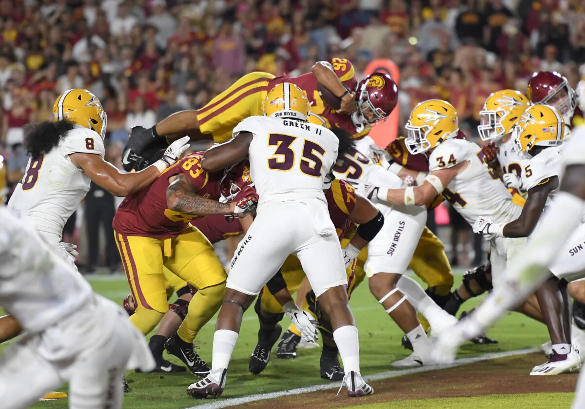 Running back Travis Dye (26) of the USC Trojans goes airborne as he scores a touchdown against Kyle Soelle (34) of the Arizona State Sun Devils during the second half at the Los Angeles Memorial Coliseum in Los Angeles, on Oct. 1, 2022. (Kevork Djansezian/Getty Images)