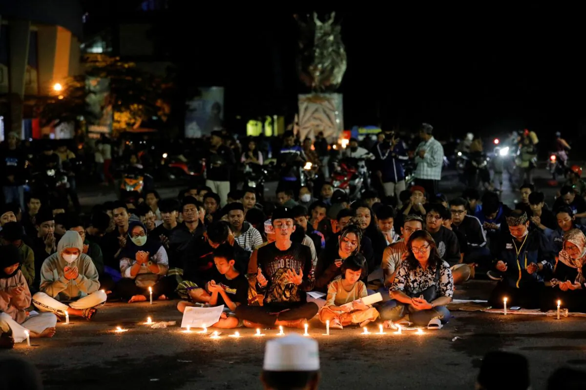 Arema Football Club supporters pray during a vigil outside the Kanjuruhan stadium to pay condolence to the victims, after a riot and stampede following soccer match between Arema vs Persebaya outside in Malang, East Java province, Indonesia, on Oct. 2, 2022. (Willy Kurniawan/Reuters)