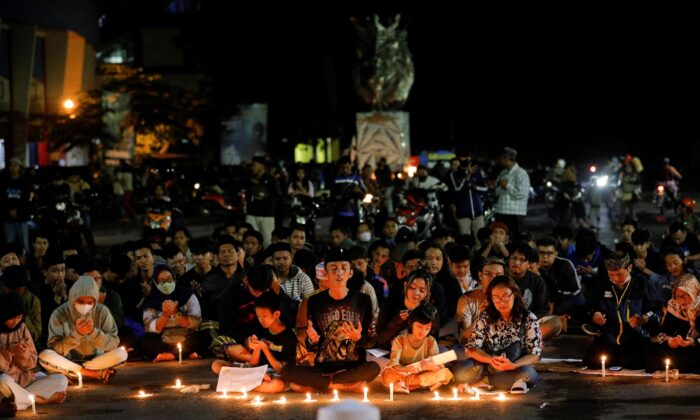 2022 年 10 月 2 日，在印度尼西亚东爪哇省玛琅市外，阿雷马与佩尔塞巴亚之间的足球比赛发生骚乱和踩踏事件后，阿雷马足球俱乐部的支持者在 Kanjuruhan 体育场外的守夜活动中祈祷，向受害者表示哀悼。（威利库尼亚万/路透社）