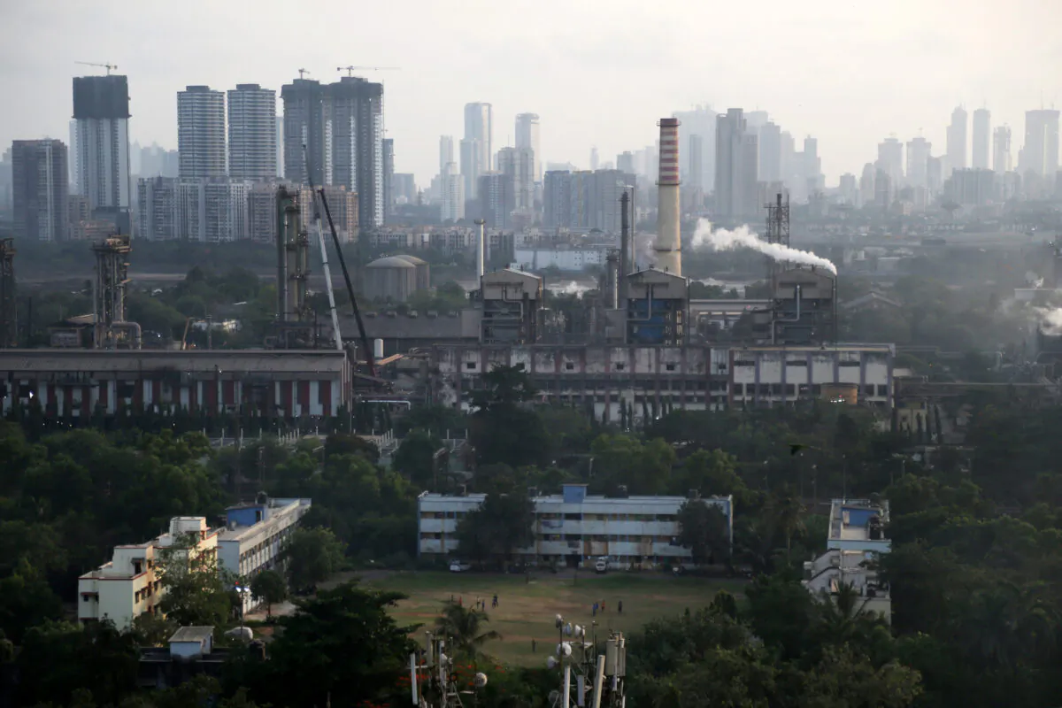Children play on a ground as smoke is emitted from chimneys of a Chemicals and Fertilizer plant on the eve of World Environment Day in Mumbai, India, on June 4, 2019. (Francis Mascarenhas/Reuters)