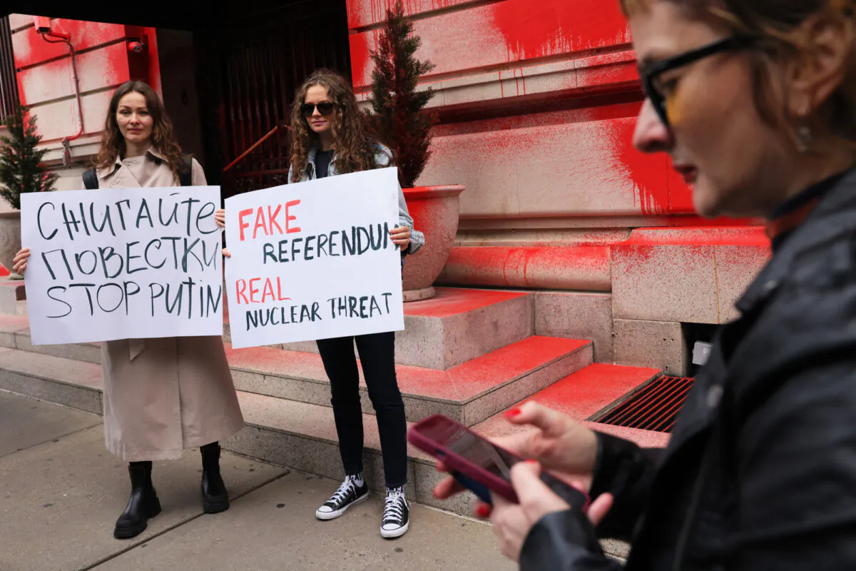 People holds protest signs as they stand in front of a vandalized Russian Consulate in New York City on Sept. 30, 2022. (Michael M. Santiago/Getty Images)