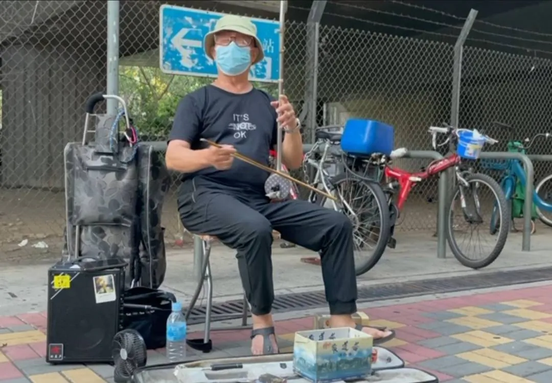 Lee Kai-sun plays the song "Glory to Hong Kong" with the erhu outside the Nam Cheong West Rail station in Hong Kong on May 22, 2021. (Cheuk Sheung-yu/The Epoch Times)