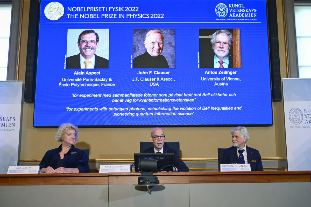 Secretary General of the Royal Swedish Academy of Sciences Hans Ellegren (C), Eva Olsson (L) and Thors Hans Hansson, members of the Nobel Committee for Physics announce the winner of the 2022 Nobel Prize in Physics, (L–R) on the screen, Alain Aspect, John F. Clauser, and Anton Zeilinger, during a press conference at the Royal Swedish Academy of Sciences in Stockholm on Oct. 4, 2022. (Jonas Ekstromer/TT News Agency via AP)