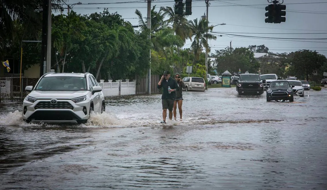 Key West, Florida, September 28, 2022 - People walk on the median surrounded by flood waters on Flagler Avenue in Key West. Hurricane Ian brushed Key West on its way to the mainland leaving flooded streets due to rain and storm surge. (El Nuevo Herald)