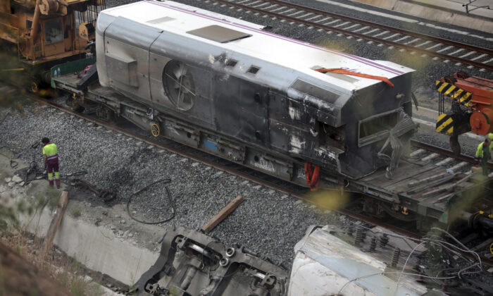 2013 年 7 月 27 日，在西班牙西北部圣地亚哥德孔波斯特拉的火车事故现场，一名工人站在损坏的火车引擎（底部 R）旁边。（Miguel Vidal/路透社）