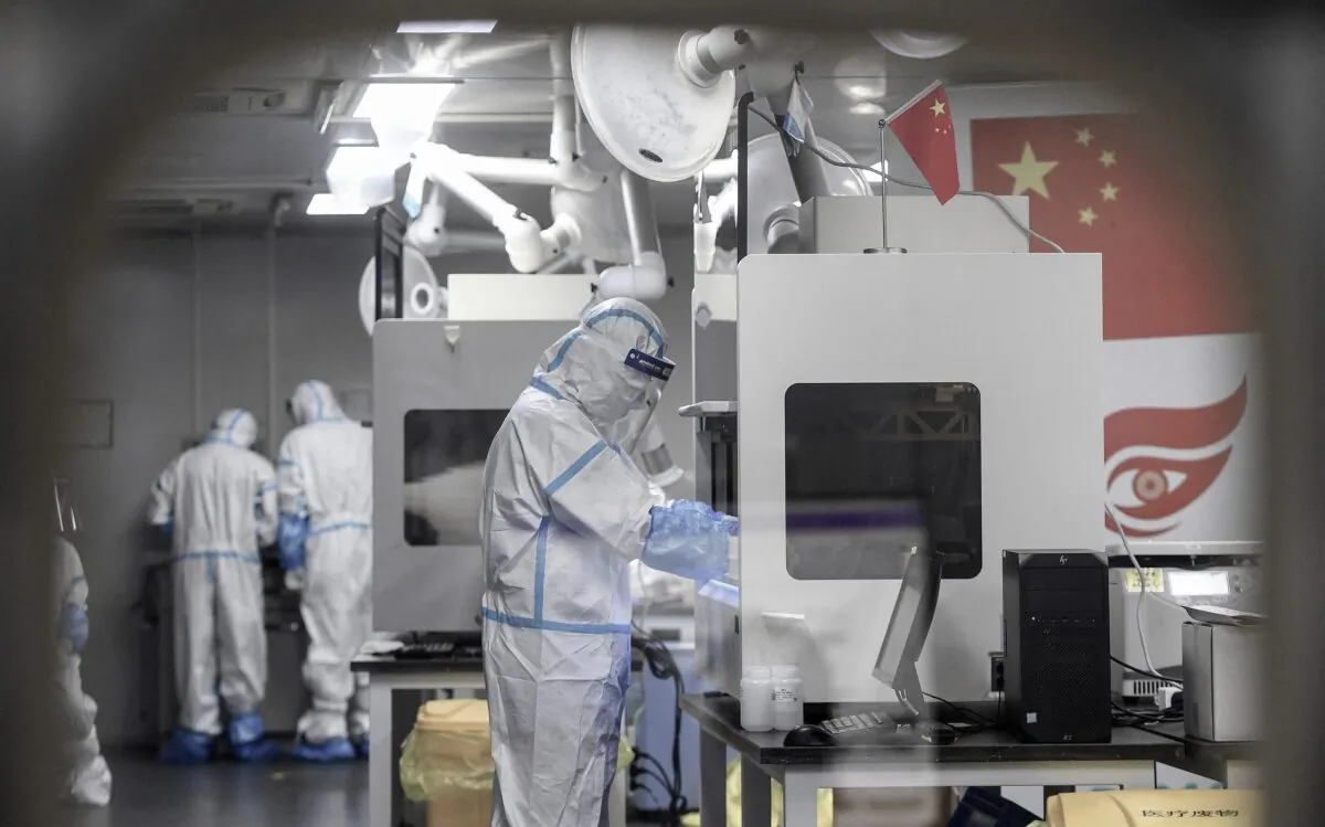 Laboratory technicians wearing personal protective equipment (PPE) work on samples to be tested for the Covid-19 coronavirus at a Covid-19 testing facility in Wuhan in China's central Hubei Province early on Aug. 5, 2021. (STR/AFP via Getty Images)
