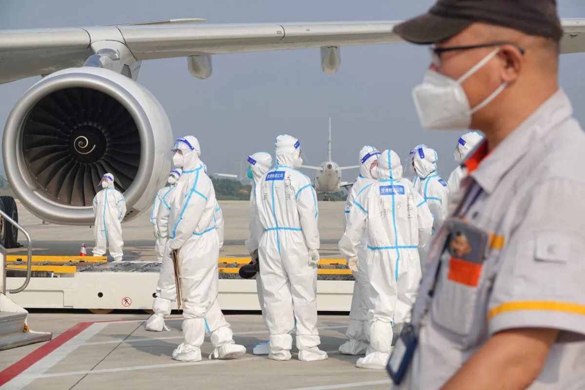 This photo shows aviation ground crew wearing personal protective equipment (PPE) working on an aircraft that flew in from abroad at the airport in Yantai in China's eastern Shandong province on Sept. 18, 2022. (Photo by STR/AFP via Getty Images)