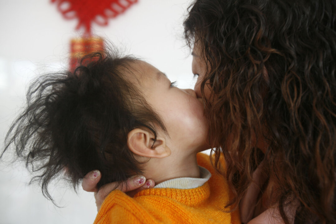 A child who suffers from cerebral palsy kisses a member of staff at the Xining Orphan and Disabled Children Welfare Center in Xining of Qinghai Province, China on Feb. 25, 2009. (China Photos/Getty Images)