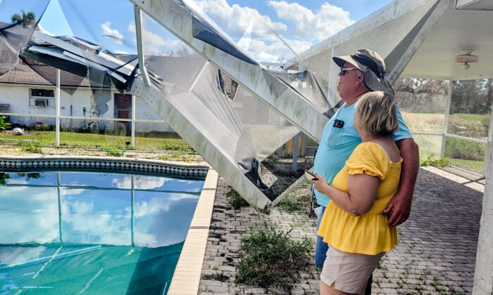 Epoch Times reporter Jann Falkenstern and her husband, Pete, survey the damage to their pool enclosure at their Punta Gorda, Fla., home on Oct. 5, 2022, a week after Hurricane Ian thrashed their property. (Courtesy of Jann Falkenstern)
