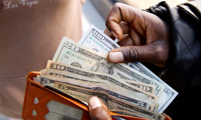 2019 年 7 月 9 日，一名男子在津巴布韦哈拉雷的一家银行提取现金后展示美元纸币。（Philimon Bulawayo/路透社）