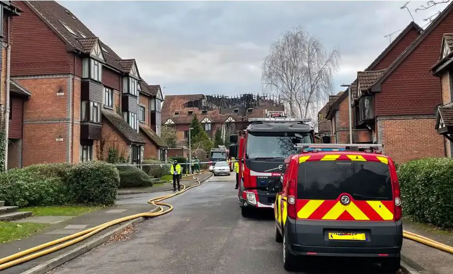 Police officers and fire engines outside a block of flats after an arson attack that claimed two lives in Reading, England, on Dec. 15, 2021. (PA) 