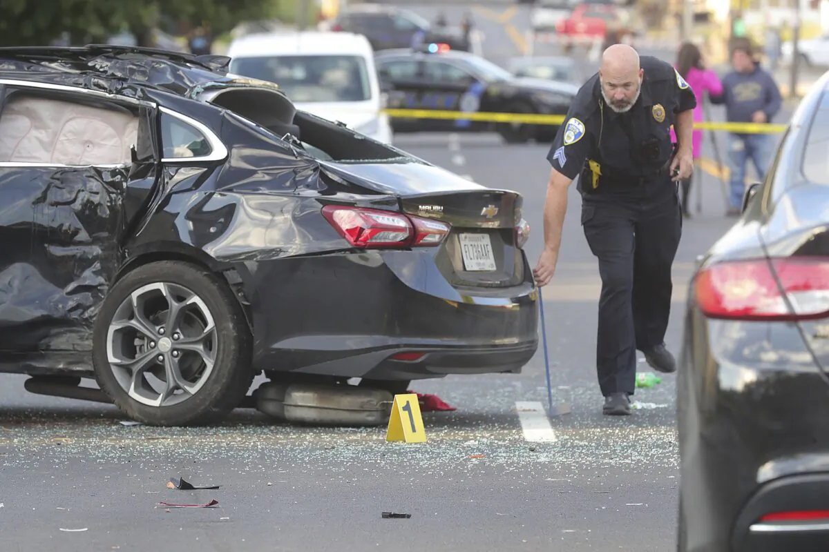 An Akron Police officer investigates the scene of a two car crash and shooting on S. Arlington Street and 6th Avenue in Akron, Ohio, on Oct. 6, 2022. (Phil Masturzo/Akron Beacon Journal via AP)