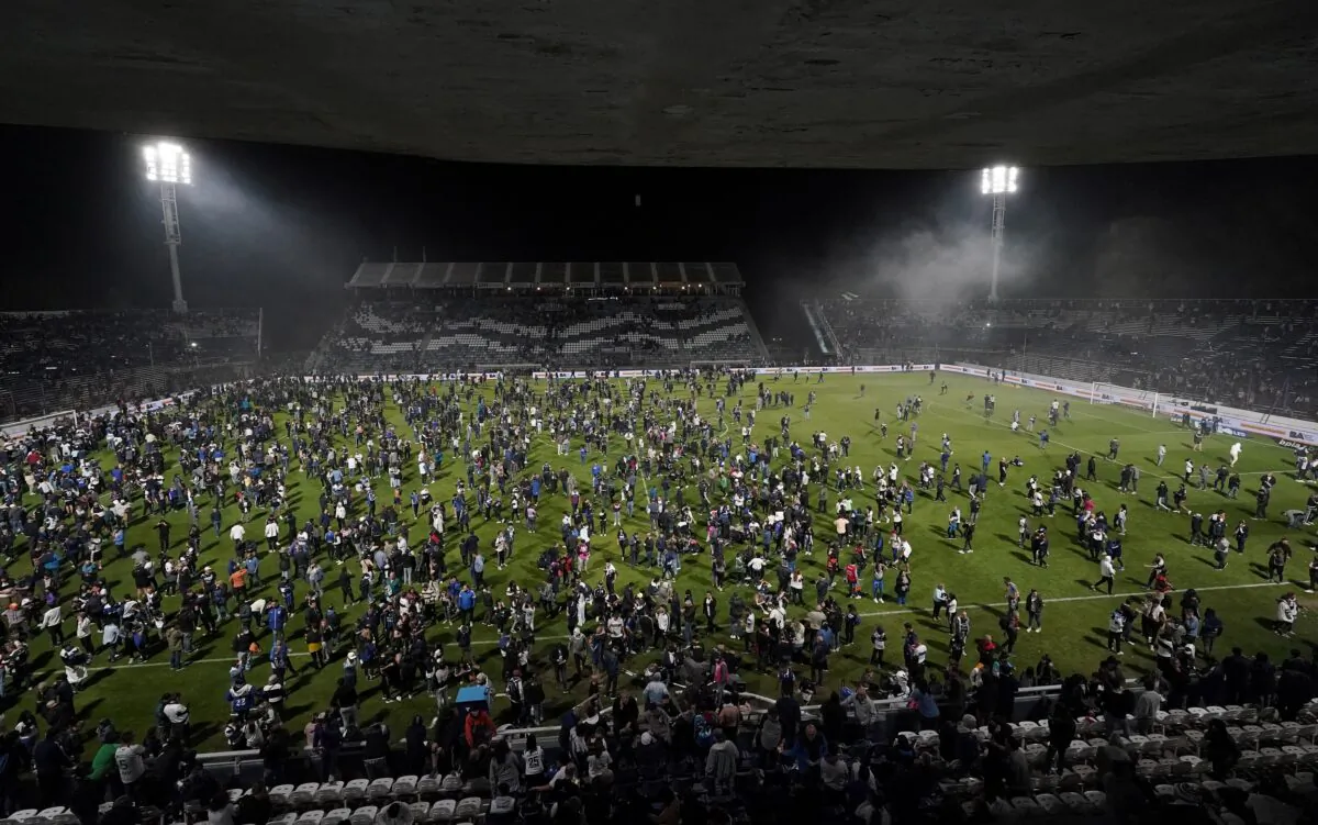 Fans of Gimnasia y Esgrima La Plata affected by tear gas invade the field after the match between Gimnasia y Esgrima La Plata and Boca Juniors in the Liga Profesional 2022 was suspended due clashes between supporters and the police outside the stadium, at Juan Carmelo Zerillo Stadium, in La Plata, Argentina, on Oct. 6, 2022. (Jose Brusco/Reuters)
