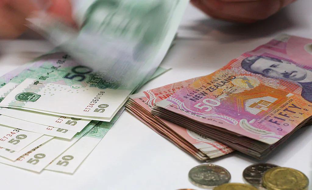 A currency exchange teller counts out Chinese Yuan alongside a stack of New Zealand dollars in Auckland, New Zealand, April 21, 2007. (Dean Treml/AFP via Getty Images)