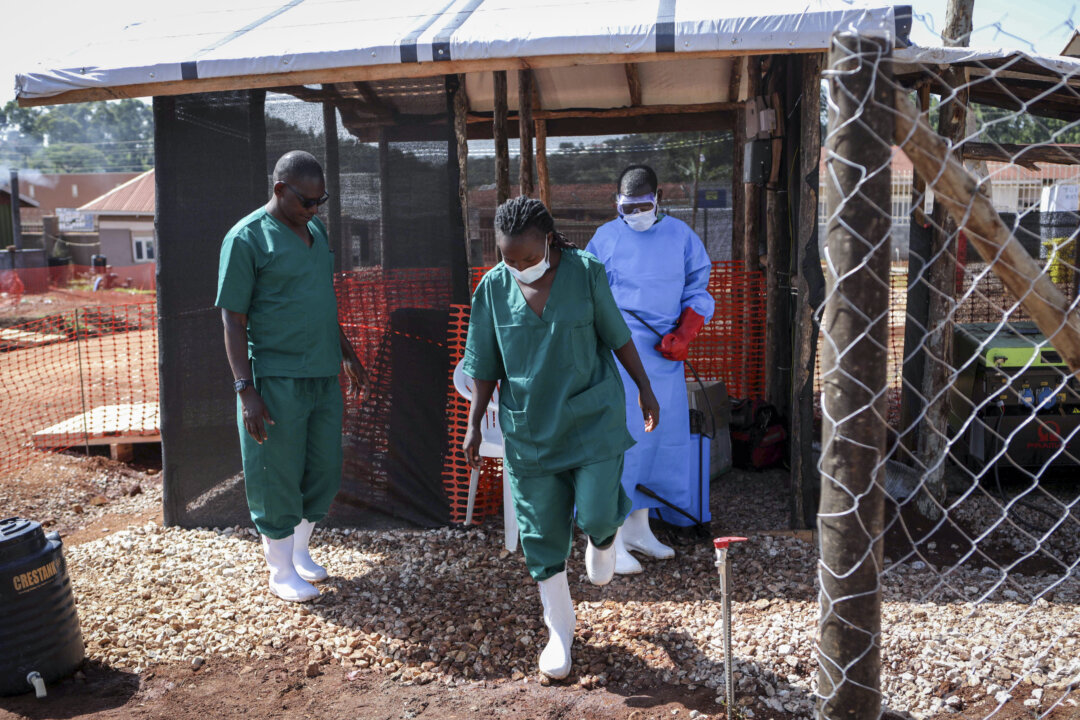 A medical attendant disinfects the rubber boots of a medical officer before leaving the Ebola isolation section of Mubende Regional Referral Hospital in Mubende, Uganda, on Sept. 29, 2022. (Hajarah Nalwadda/AP Photo)