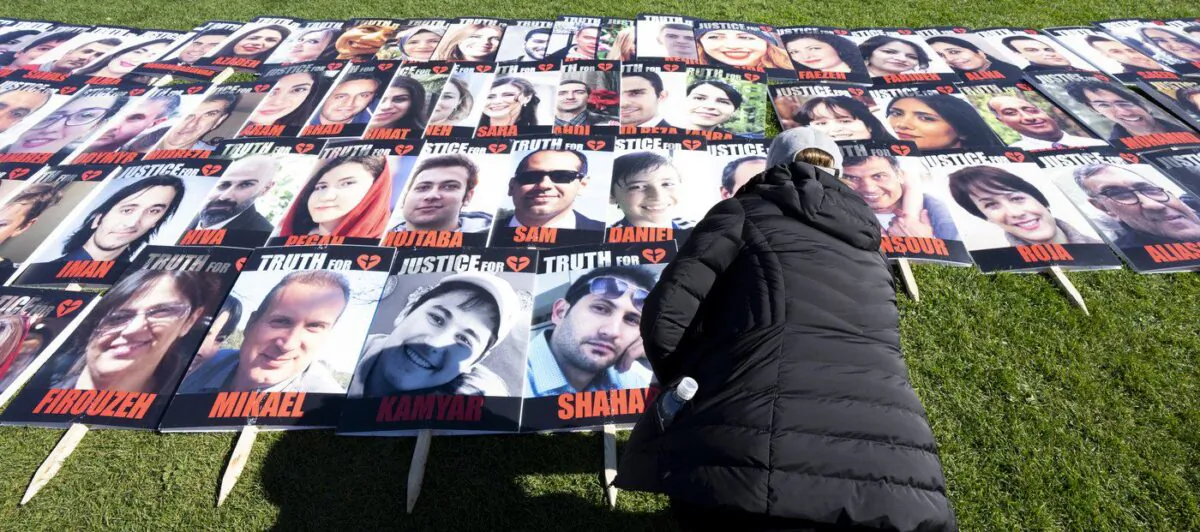 A woman places a placard with the photo of a person killed on Flight 752 during a protest on Parliament Hill, Oct. 4, 2022 in Ottawa. (The Canadian Press/Adrian Wyld)